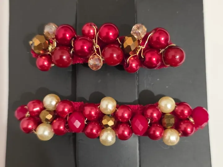 Dos pinzas Loft de terciopelo rojo con perlas rojas, perlas crema y cristales dorados, sobre la tarjeta de Carolina Atelier