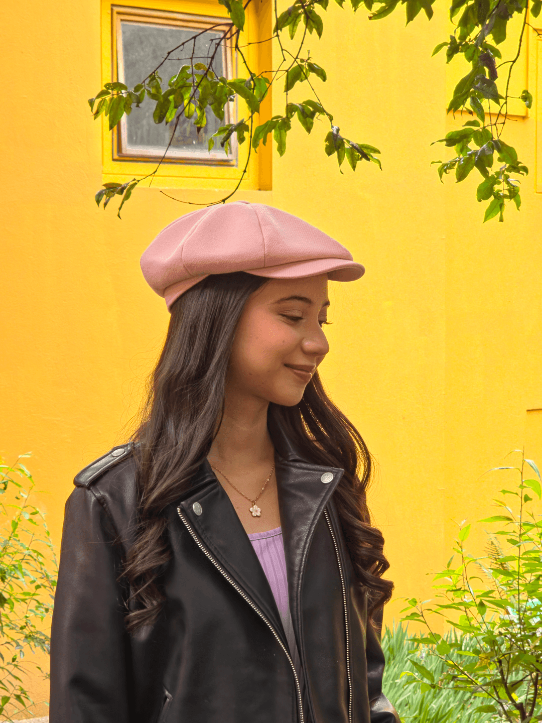 Clienta con boina Gatsby rosada frente a una pared amarilla